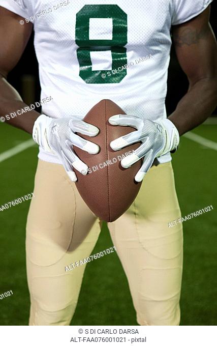 Football player holding football, cropped