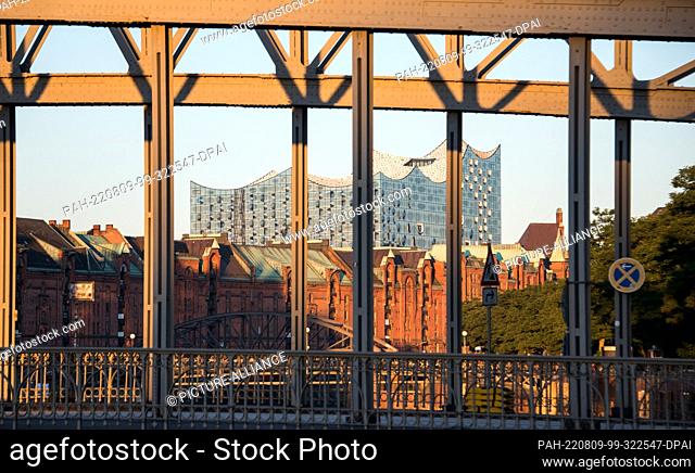 09 August 2022, Hamburg: The Elbphilharmonie and the Speicherstadt shine in the light of the rising sun. Photo: Daniel Bockwoldt/dpa