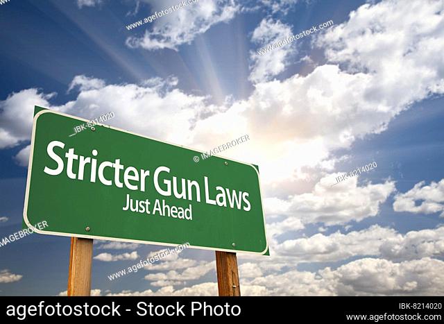 Stricter gun laws green road sign with dramatic clouds and sky
