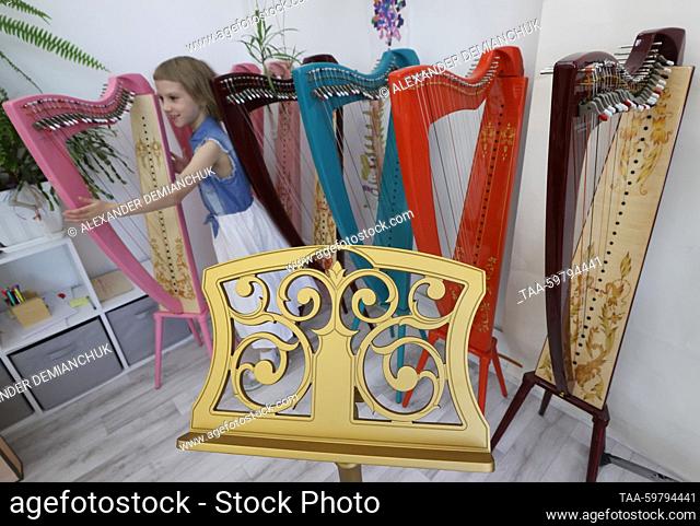 RUSSIA, ST PETERSBURG - JUNE 13, 2023: A child looks at harps in an outlet shop at the Resonance Harps musical instrument factory