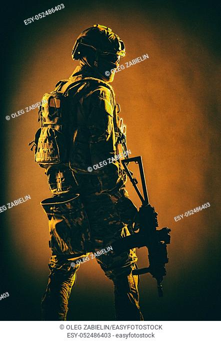 Low key studio shoot of army special forces soldier, commando fighter in mask, ballistic glasses, tactical helmet and battle uniform