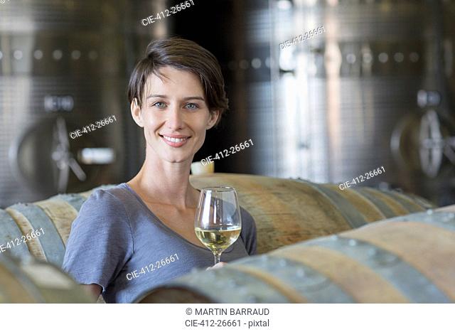 Portrait confident vintner drinking white wine in winery cellar