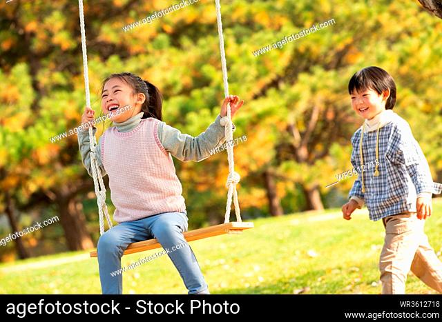 Happy children on the swings in the park