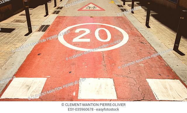 in front of a red pedestrian crossing, white paint forbidden to exceed the speed of 20
