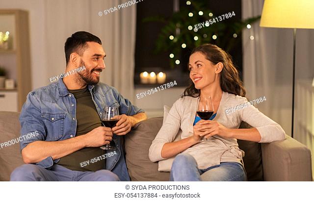 happy couple drinking red wine at home in evening