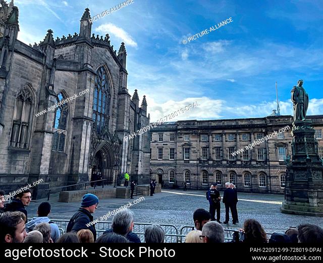 12 September 2022, Great Britain, Edinburgh: In front of the main portal of St. Giles Cathedral, police officers and people are waiting for the Queen's coffin