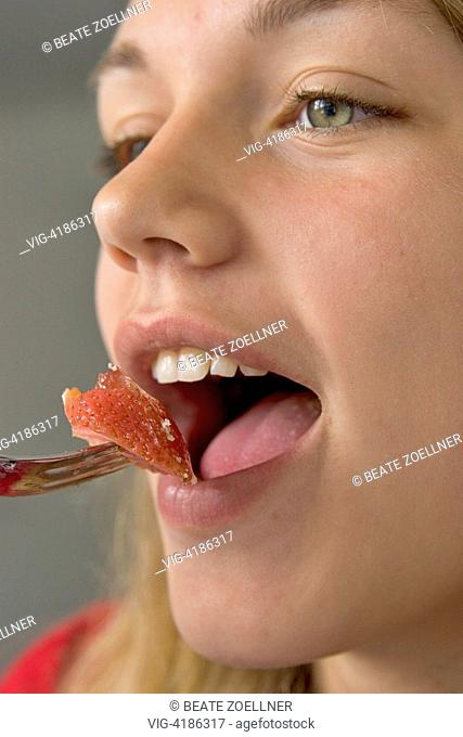 Close-up : girl opens her mouth and puts a piece of strawberry with a - , , Germany, 17/06/2006