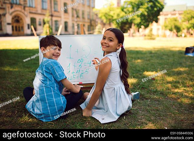 Smiling Schoolmate Having Lesson In Nature. Study Outside Concept. Writing On Whiteboard
