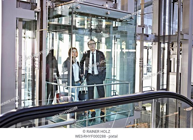 Germany, Cologne, Young woman and mature man in escalator at airport