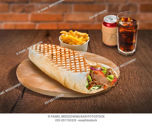Gyros pita sandwich with french fries and cola on wooden background. For fast food restaurant design or fast food menu
