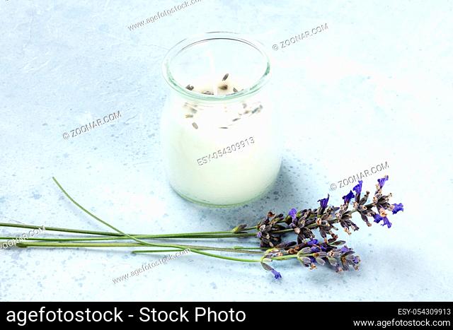 A lavender scented candle with lavender flowers and a place for text. Zero waste Christmas concept, a handmade New Year gift in a recycled glass jar