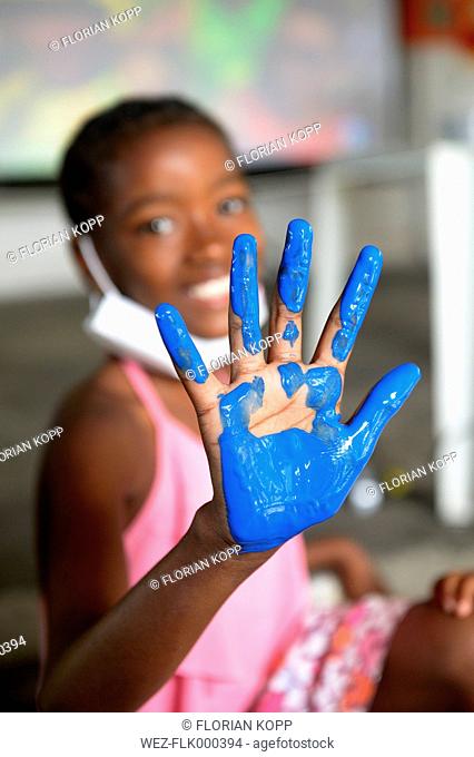 Brazil, Rio de Janeiro, Duque de Caxias, girl showing her palm with blue finger colour