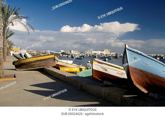 View of fishing boats pulled ashore with view of the harbour and Fort Qaitbey in the distance