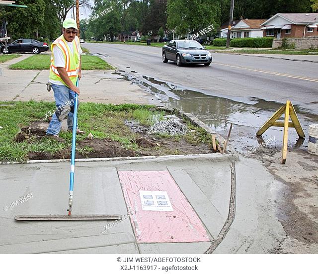 Detroit, Michigan - Workers install a curb ramp at a street intersection to allow access for people with disabilities  The ramps are required by the Americans...