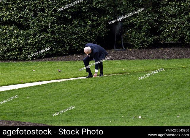 United States President Joe Biden stops to pick up a leaf from a ground on the South Lawn of the White House in Washington before his departure to Portland