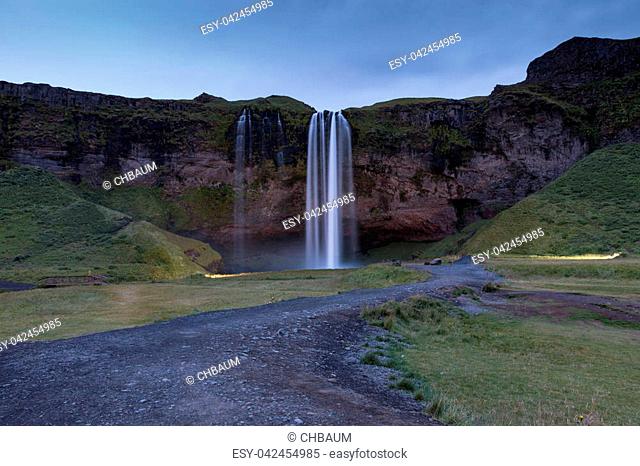 Night shot of world famous Seljalandsfoss, a majestic waterfall in southern Iceland, coming down over a cliff, fed by a glacier