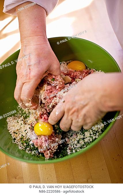parmesan meatball ingredients in a bowl being processed by hand