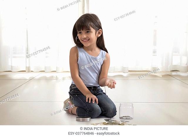 little girl with coin box and coins on floor