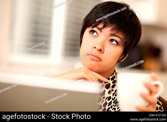 Contemplative Pretty Mixed Race Woman Holding Cup Using Laptop