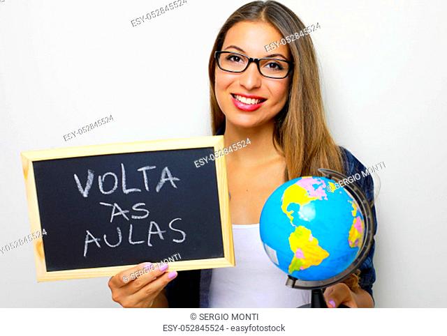 Brazilian young female teacher holding globe and blackboard with portuguese written ""Volta as aulas"" (Back to school)