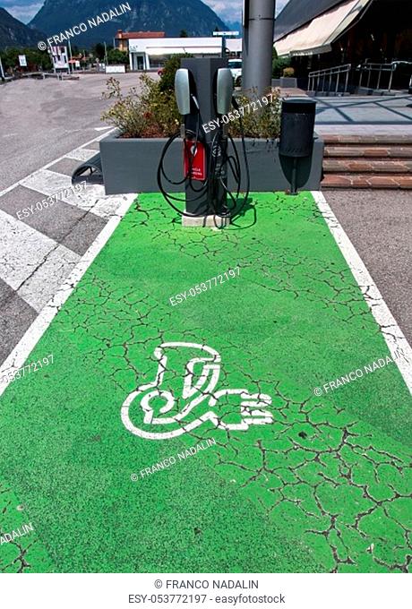 Electric Vehicle (EV) Charging Station parking spot with icon text on aging green painted pavement