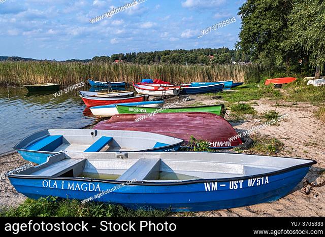 Small boats on shore of Narie Lake located in Ilawa Lakeland region, view from Kretowiny village, Ostroda County, Warmia and Mazury province of Poland