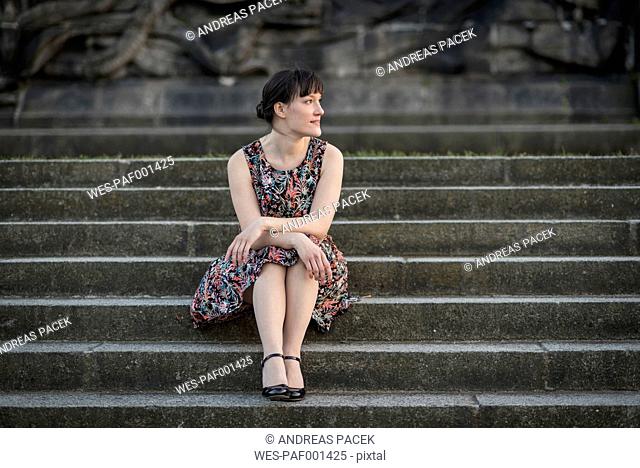 Germany, Koblenz, Deutsches Eck, young woman sitting on stairs