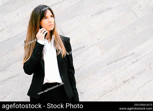 Upset Businesswoman talking on telephone standing outside office building. Social family, business and communication problem concept