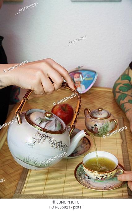 A hand pouring green tea into cup