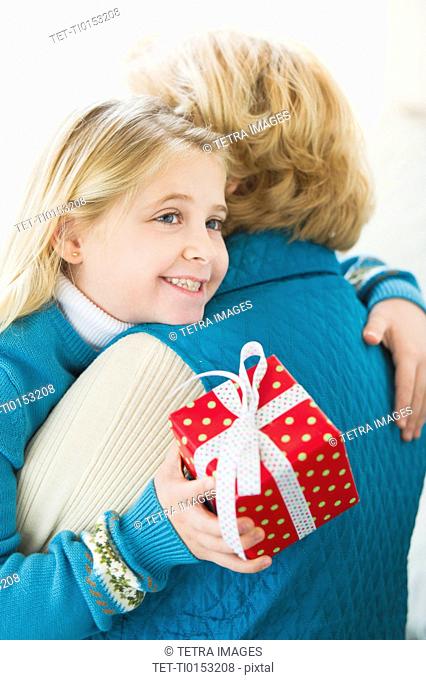 Granddaughter 8-9 hugging grandmother and holding gift
