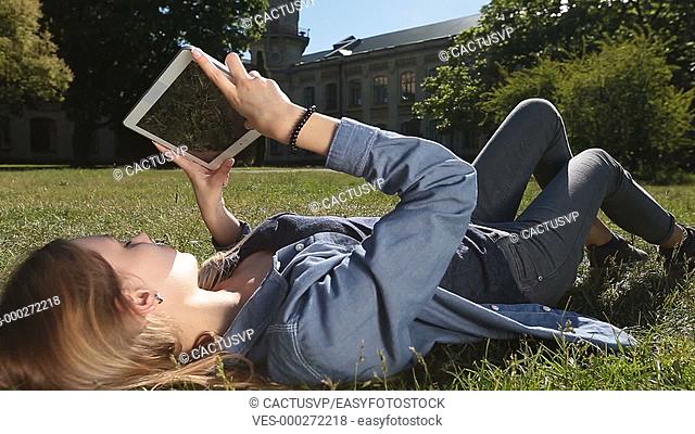 Cute female student studying with tablet in park