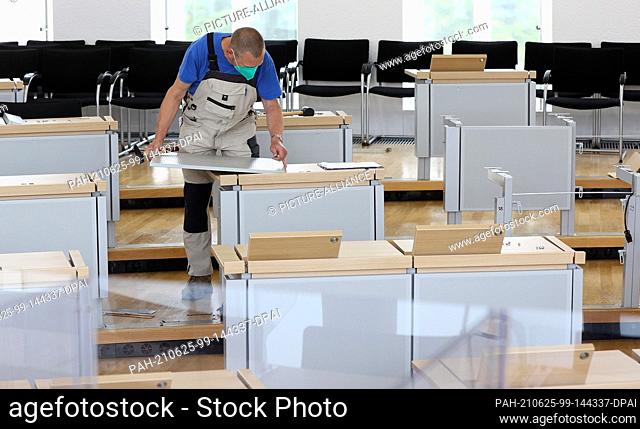 25 June 2021, Saxony-Anhalt, Magdeburg: A carpenter handles a tabletop in the plenary chamber of the Saxony-Anhalt state parliament