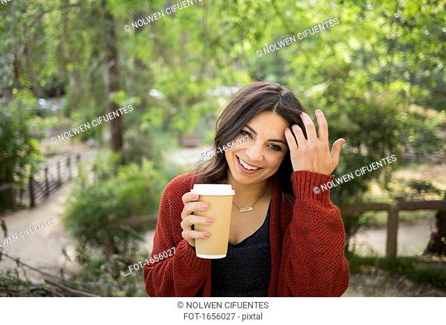 Cheerful woman holding disposable glass in park