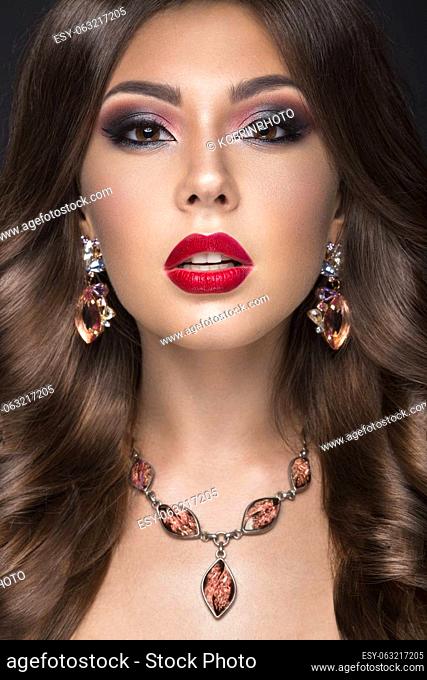 Beautiful woman with arabic make-up, red lips and curls. Beauty face. Picture taken in the studio on a gray background