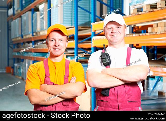 two young handsome workers man in uniform in front of warehouse rack arrangement stillages