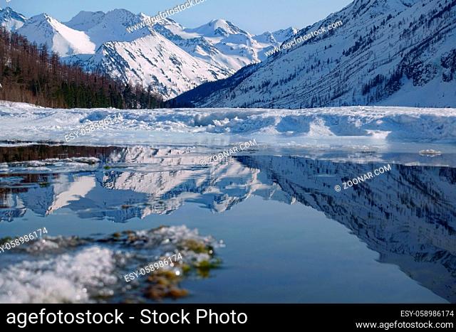 Winter landscape with mountain lake and high mountains reflected