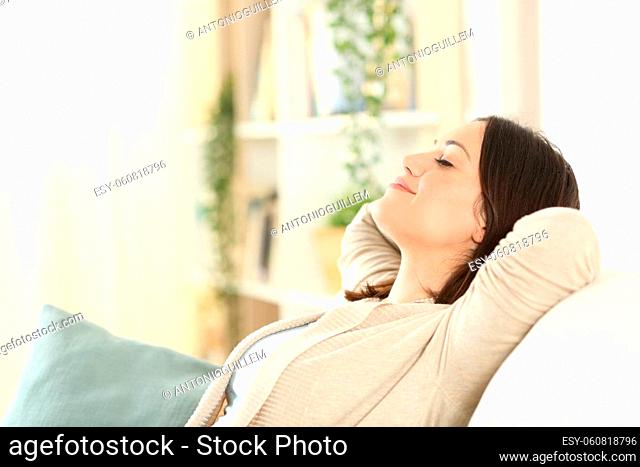 Woman resting and relaxing sitting on a comfortable couch in the living room at home