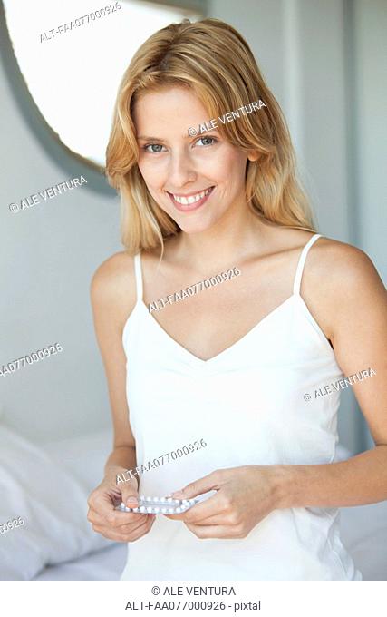 Young woman holding birth control pills, portrait