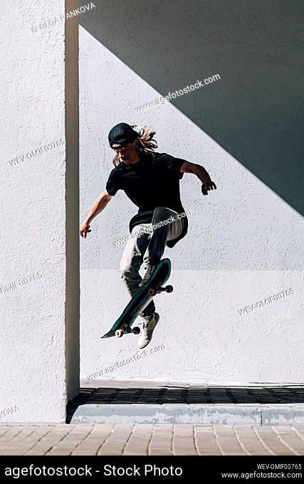 Man with skateboard jumping in front of wall