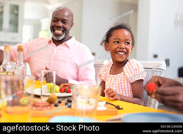 Happy african american girl having lunch with family at home on thanksgiving day
