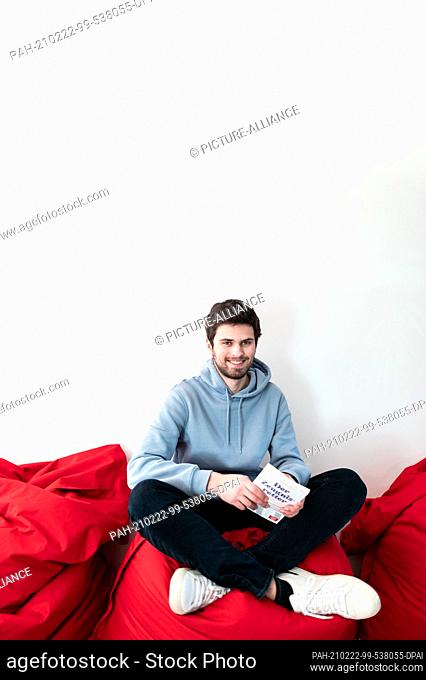 19 February 2021, North Rhine-Westphalia, Duesseldorf: Student and bestselling author Tim Nießner sits on a beanbag with his new book ""Der Zeugnisretter""