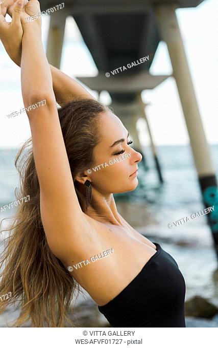 Beautiful young woman with closed eyes wearing swimsuit at the seafront