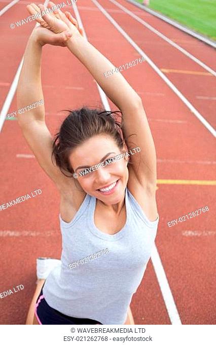 Woman on a track in a stadium stretching her arms