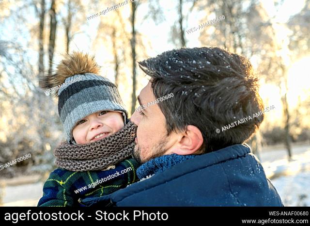 Smiling boy with father wearing warm clothing in winter park