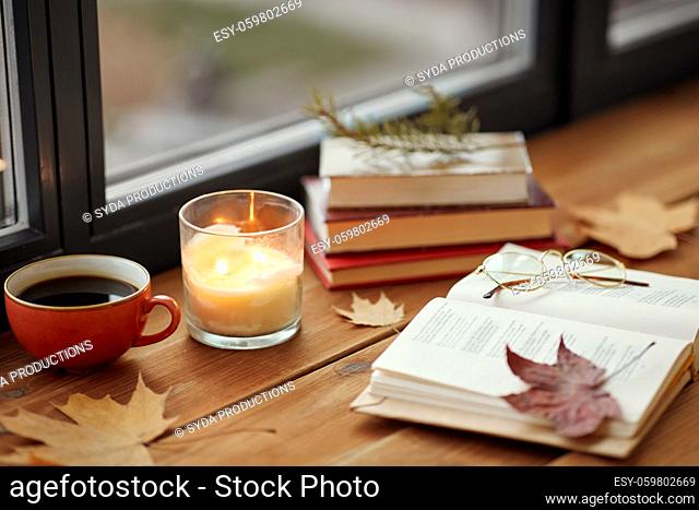 book, coffee and candle on window sill in autumn