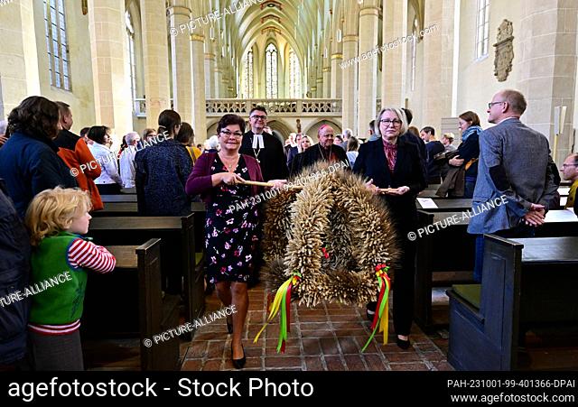 01 October 2023, Thuringia, Erfurt: Thuringian countrywomen carry a harvest crown from the Predigerkirche in Erfurt. Thuringia celebrates the harvest festival...