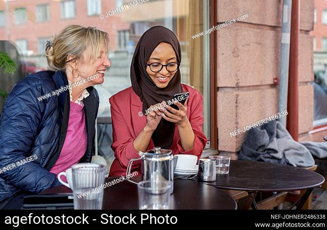 Female friends having coffee in outdoor cafe