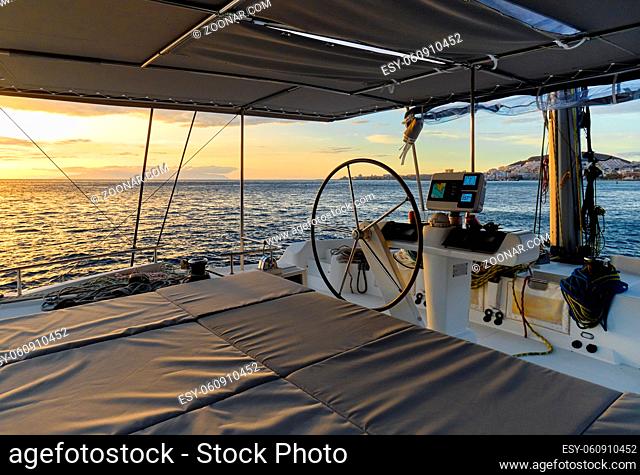 Idyllic scenery glowing sun down Ocean calm water view from catamaran flybridge open deck, modern luxury yacht equipped with navigation dashboard devices