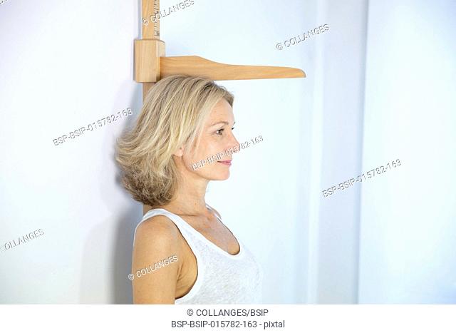 Woman measuring herself with a height measuring rod