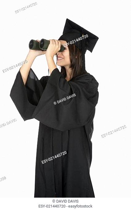 Beautiful Caucasian woman wearing in a black graduation gown and looking through binoculars, isolated on a white background